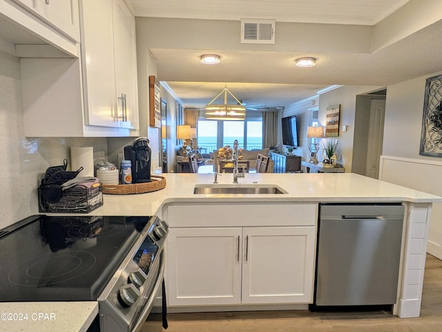 kitchen featuring appliances with stainless steel finishes, sink, light wood-type flooring, and kitchen peninsula