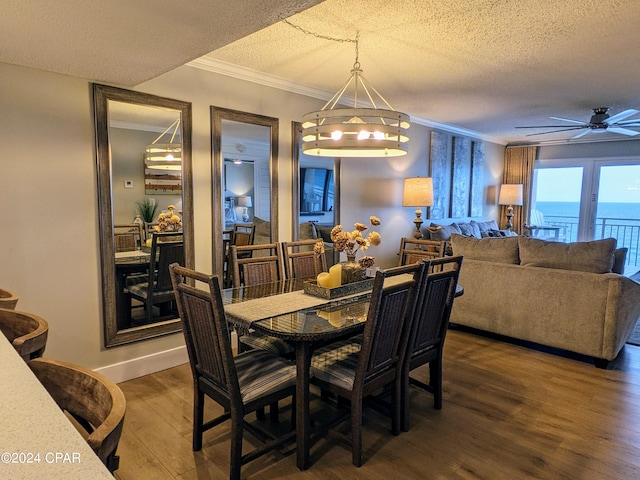 dining area featuring a water view, dark hardwood / wood-style flooring, ceiling fan with notable chandelier, crown molding, and a textured ceiling