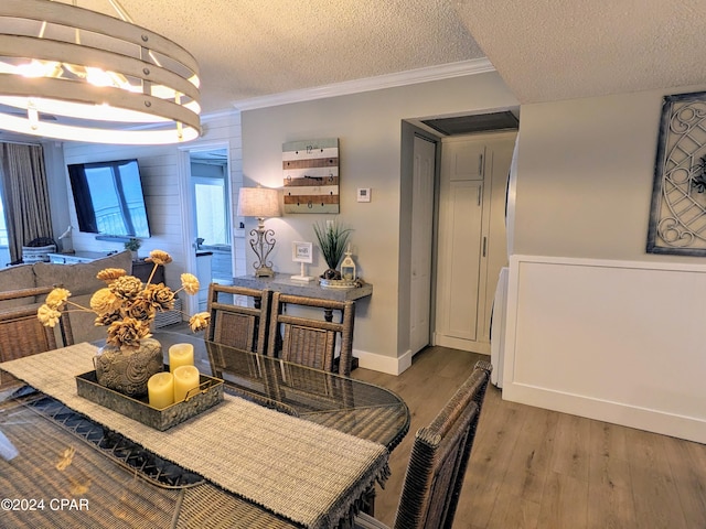 dining area with ornamental molding, a textured ceiling, and hardwood / wood-style flooring