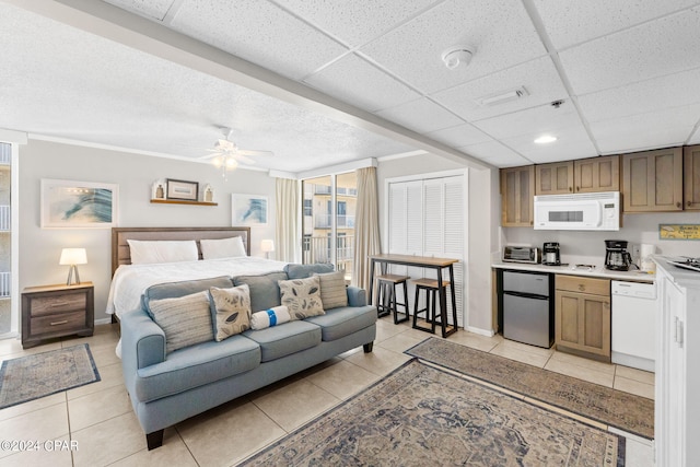 tiled bedroom with stainless steel fridge, a closet, a drop ceiling, and ceiling fan