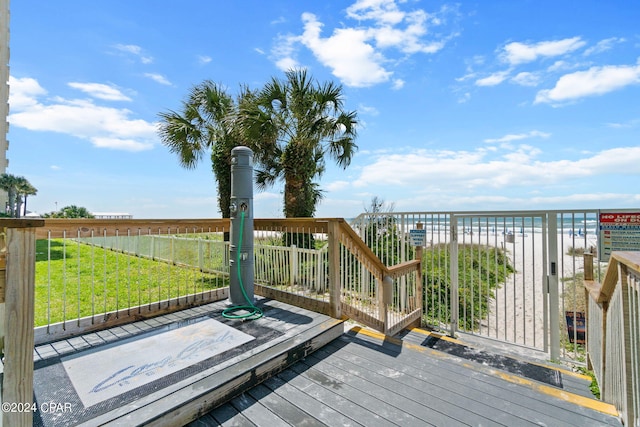 deck featuring a lawn, a water view, and a beach view