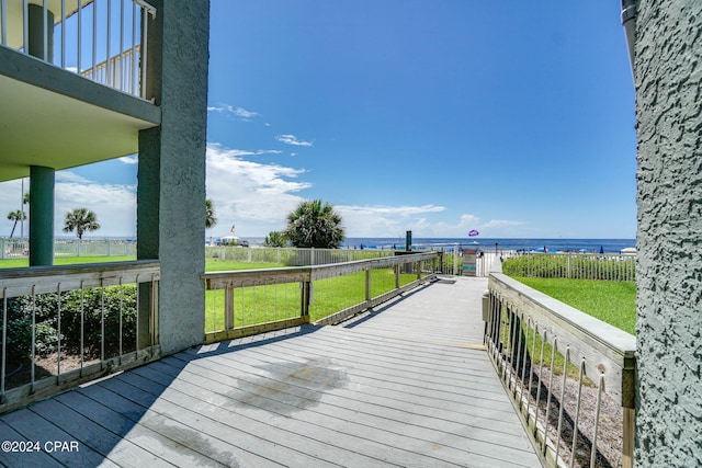 deck with a water view and a lawn