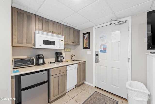 kitchen featuring a paneled ceiling, sink, light tile patterned flooring, and white appliances