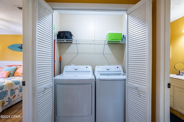 clothes washing area with independent washer and dryer and a textured ceiling