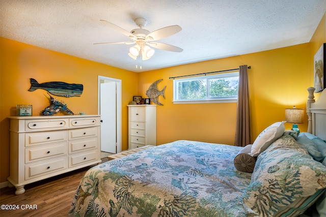 bedroom featuring dark hardwood / wood-style flooring, ceiling fan, and a textured ceiling