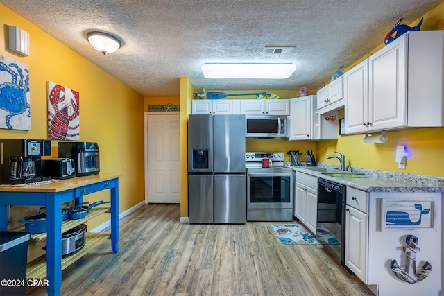 kitchen featuring appliances with stainless steel finishes, sink, a textured ceiling, and hardwood / wood-style floors