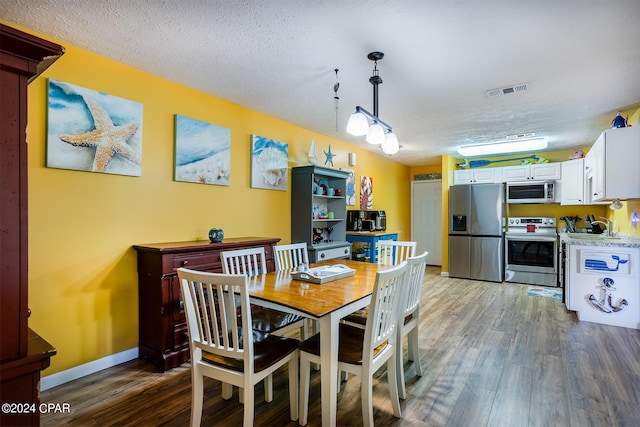 dining space featuring a textured ceiling and hardwood / wood-style floors