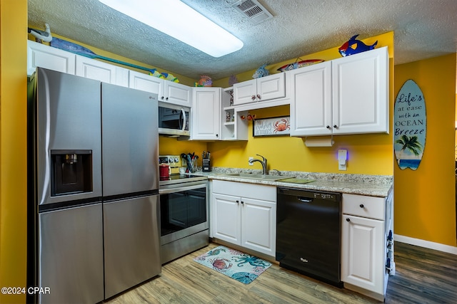 kitchen with white cabinetry, hardwood / wood-style flooring, a textured ceiling, and stainless steel appliances