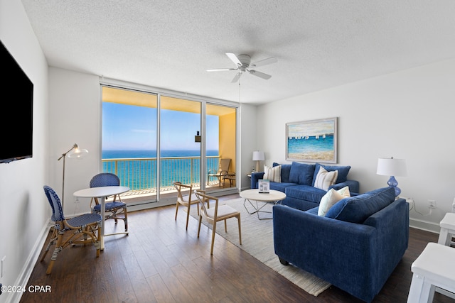 living room with a textured ceiling, ceiling fan, a water view, and hardwood / wood-style floors