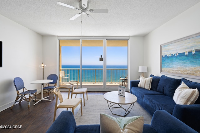 living room with a textured ceiling, ceiling fan, a water view, and hardwood / wood-style floors