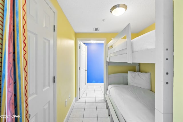 bedroom with a textured ceiling and light tile floors