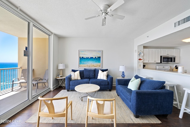 living room with hardwood / wood-style flooring, ceiling fan, a water view, and a textured ceiling