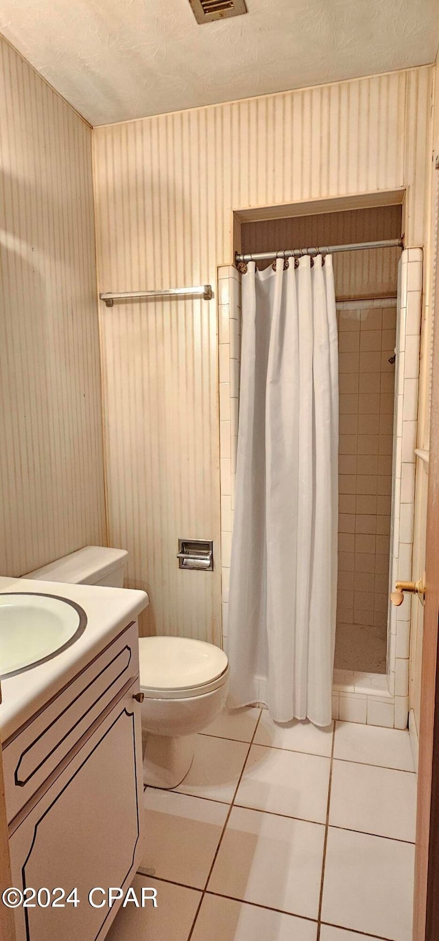 bathroom featuring tile flooring, walk in shower, vanity, and toilet