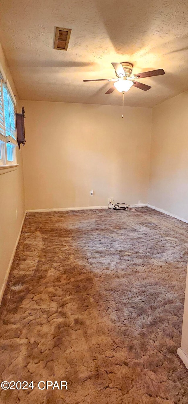 carpeted spare room featuring ceiling fan and a textured ceiling