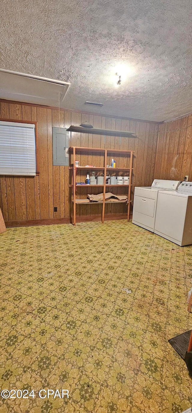 basement with wood walls, separate washer and dryer, a textured ceiling, and carpet flooring