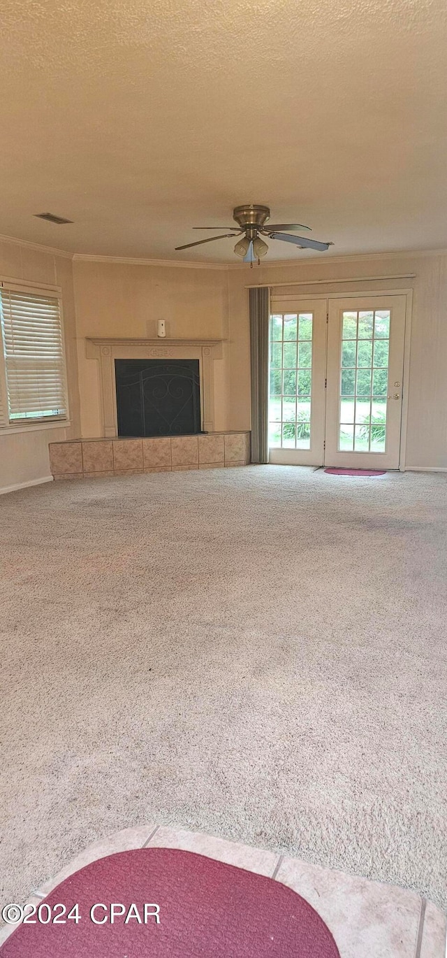 unfurnished living room with carpet floors, a textured ceiling, a tile fireplace, and ceiling fan