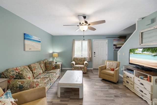 living area with light wood-style floors, baseboards, and a ceiling fan