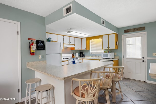 kitchen featuring sink, a breakfast bar, white appliances, and white cabinetry