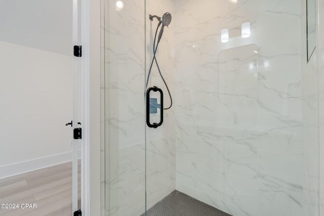 bathroom with hardwood / wood-style floors and a shower with shower door