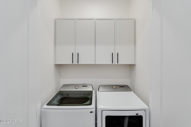 clothes washing area with cabinets and washer and clothes dryer