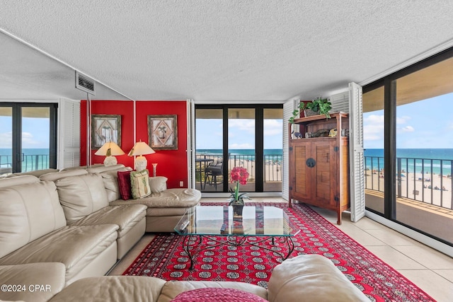 tiled living room with plenty of natural light, a textured ceiling, expansive windows, and a water view