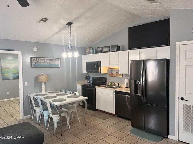 kitchen with hanging light fixtures, white cabinets, vaulted ceiling, light tile patterned flooring, and black appliances