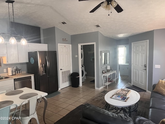 living room with washer / dryer, a textured ceiling, ceiling fan, and light tile patterned flooring