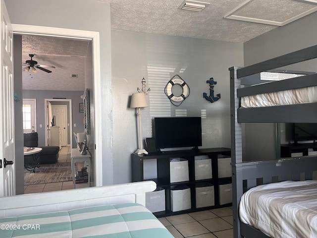 bedroom featuring ensuite bathroom, light tile patterned flooring, and a textured ceiling