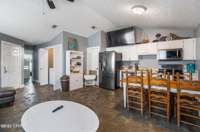 kitchen featuring ceiling fan, a textured ceiling, lofted ceiling, white cabinets, and appliances with stainless steel finishes