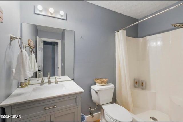 bathroom featuring curtained shower, vanity, a textured ceiling, and toilet