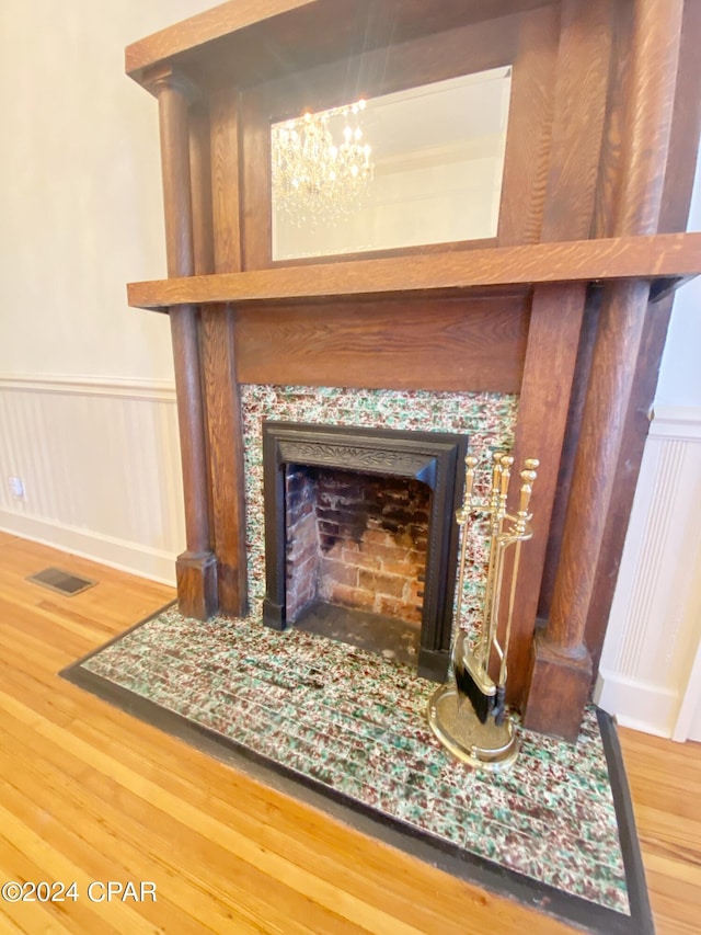 details featuring wood-type flooring, a notable chandelier, and a premium fireplace