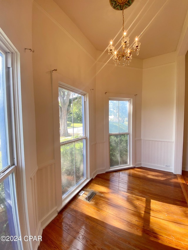 unfurnished dining area featuring hardwood / wood-style floors and a chandelier