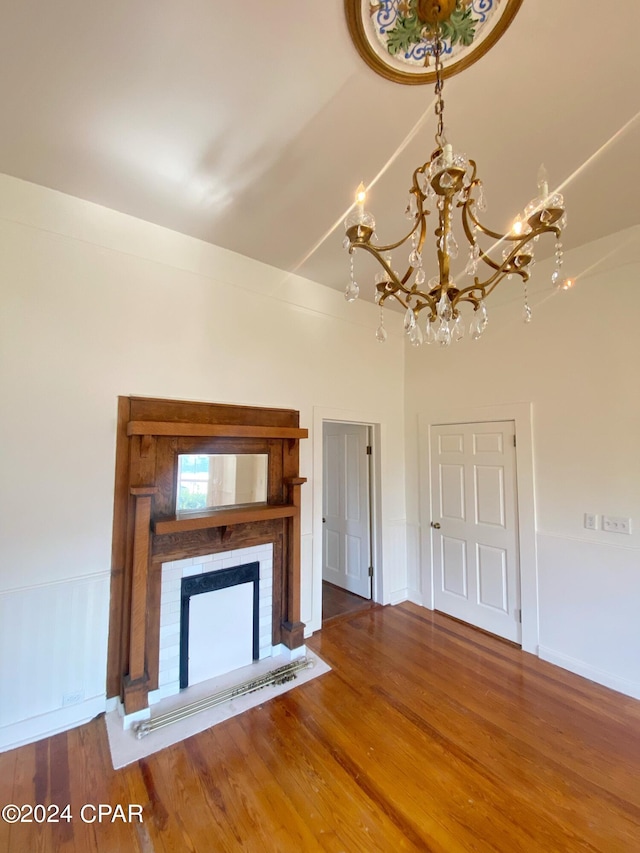 unfurnished living room with hardwood / wood-style flooring, a notable chandelier, and vaulted ceiling