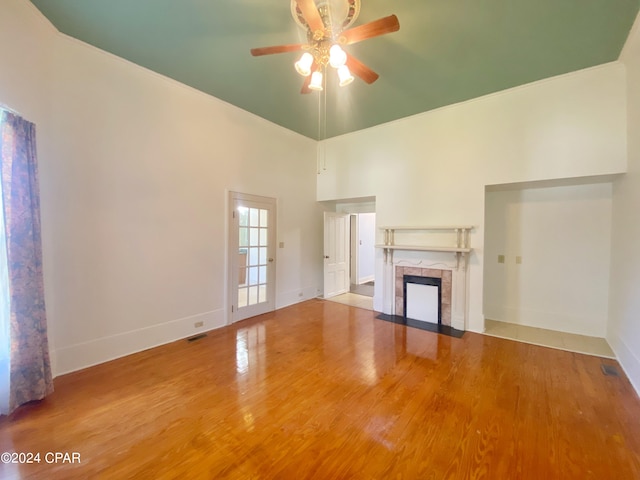 unfurnished living room with a towering ceiling, hardwood / wood-style flooring, and ceiling fan