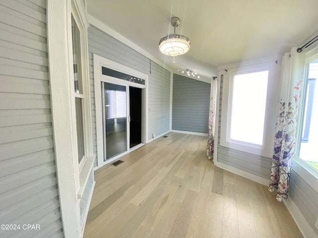 interior space featuring light wood-type flooring and wooden walls