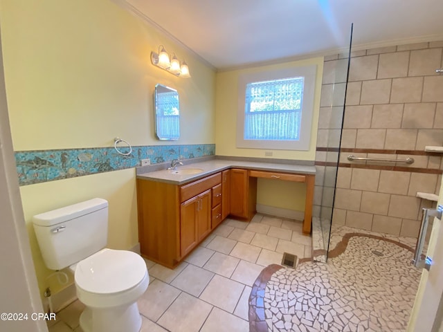 bathroom featuring crown molding, tile patterned floors, toilet, a tile shower, and vanity