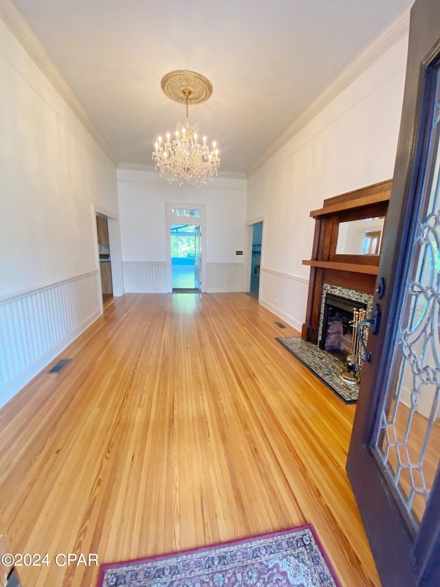 unfurnished living room with ornamental molding, a chandelier, and hardwood / wood-style flooring