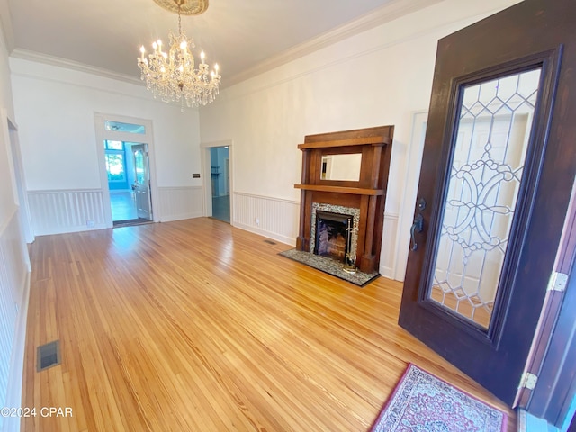 unfurnished living room with crown molding, a notable chandelier, and light hardwood / wood-style flooring