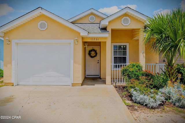 ranch-style house featuring roof with shingles, covered porch, stucco siding, a garage, and driveway