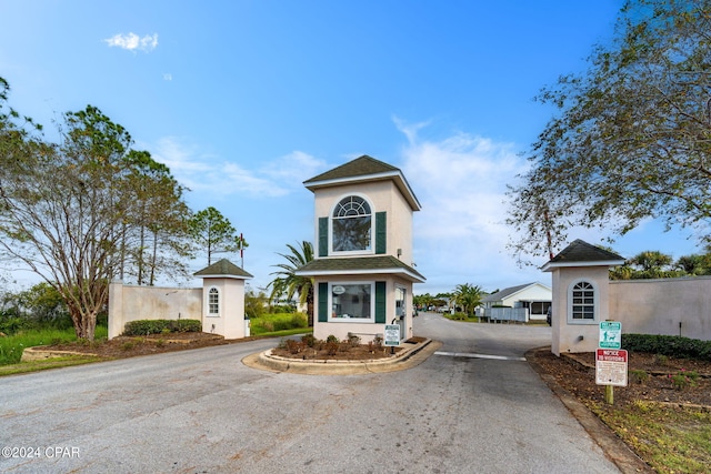 view of front of property with aphalt driveway, stucco siding, and roof with shingles