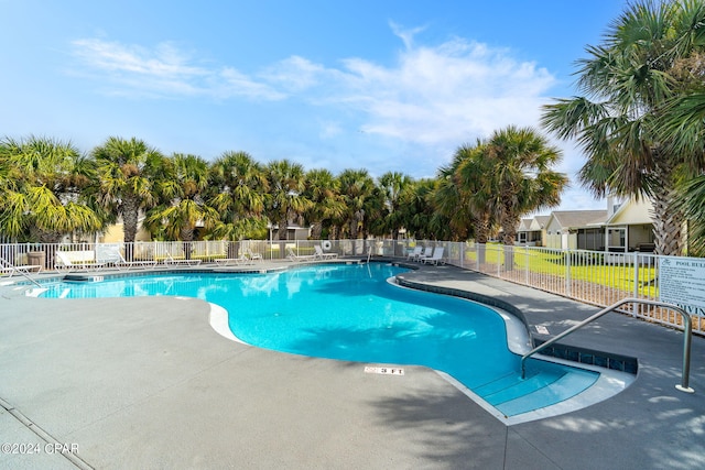 community pool with a patio and fence