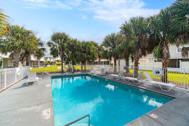 community pool featuring a patio area, fence, and a lawn