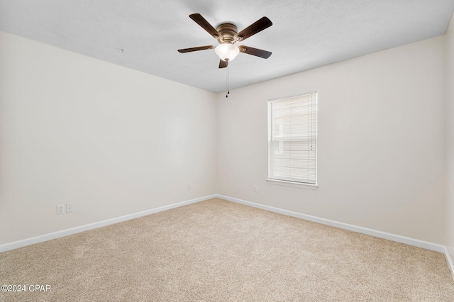 carpeted spare room with a ceiling fan and baseboards