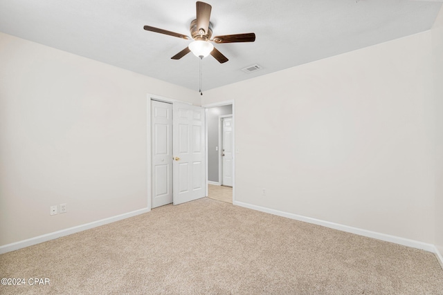 empty room with ceiling fan, light colored carpet, visible vents, and baseboards