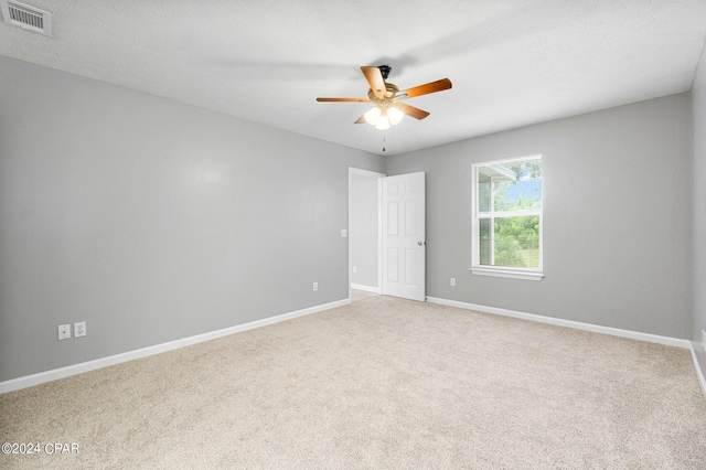 carpeted spare room featuring visible vents, ceiling fan, and baseboards