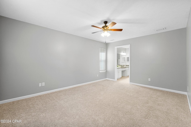 unfurnished room featuring a ceiling fan, visible vents, light colored carpet, and baseboards