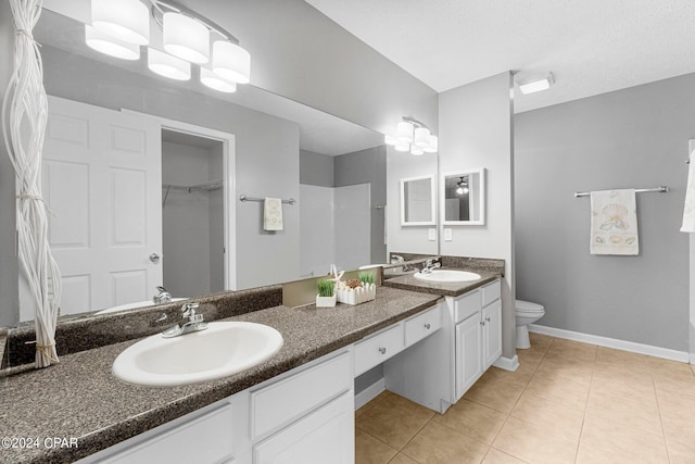 bathroom with tile patterned floors, double vanity, toilet, and a sink