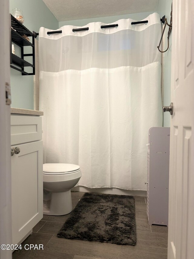 bathroom with vanity, hardwood / wood-style flooring, a textured ceiling, and toilet