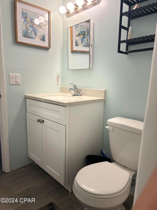 bathroom with toilet, vanity, and wood-type flooring