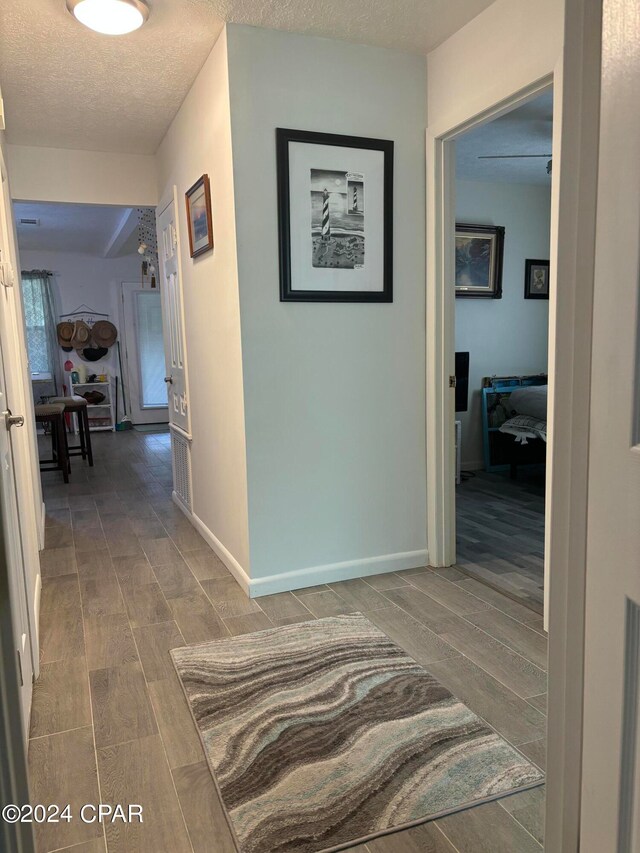 hall with wood-type flooring and a textured ceiling